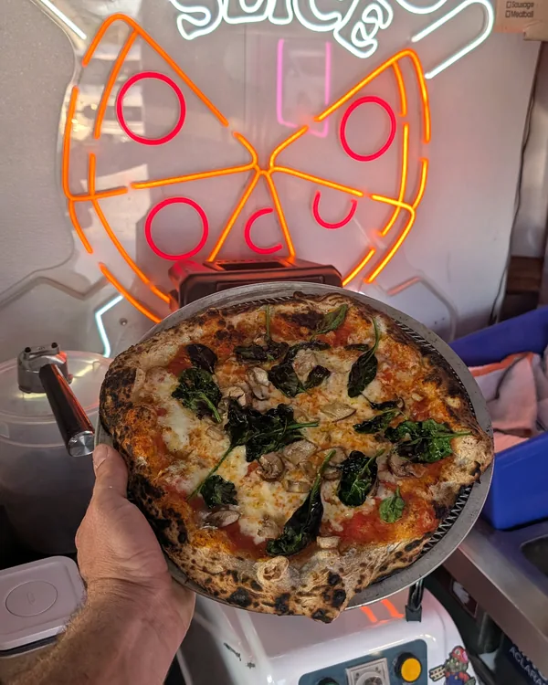 Pizza under the Jimbo Slice neon sign